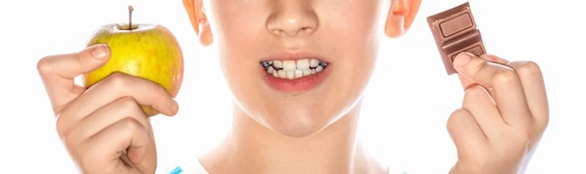 Chłopiec trzymający jabłko i czekoladę