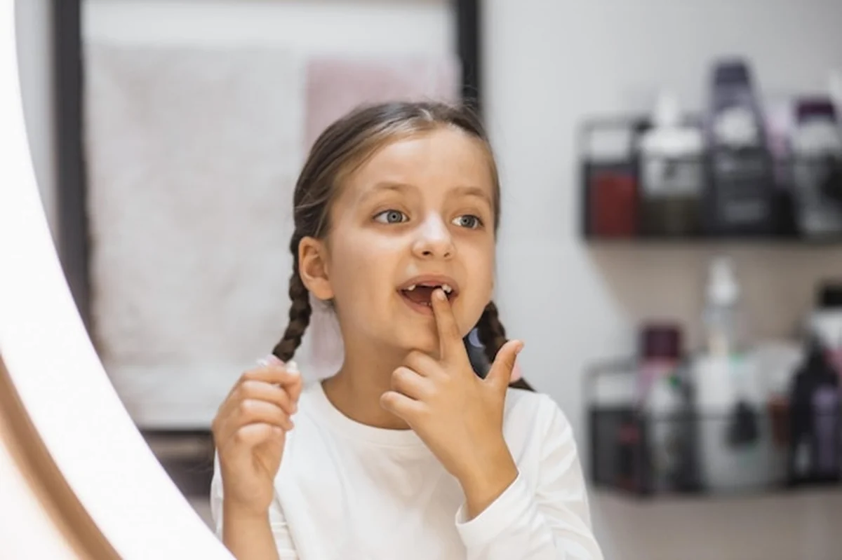 Dziewczynka bada upadły ząb przed lustrem