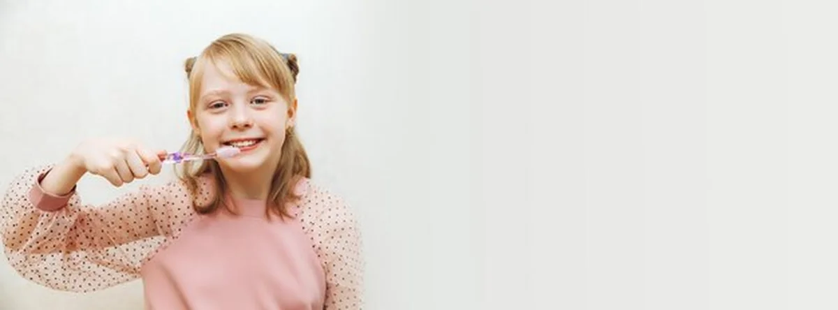 Dziewczynka myjąca zęby szczoteczką na białym tle