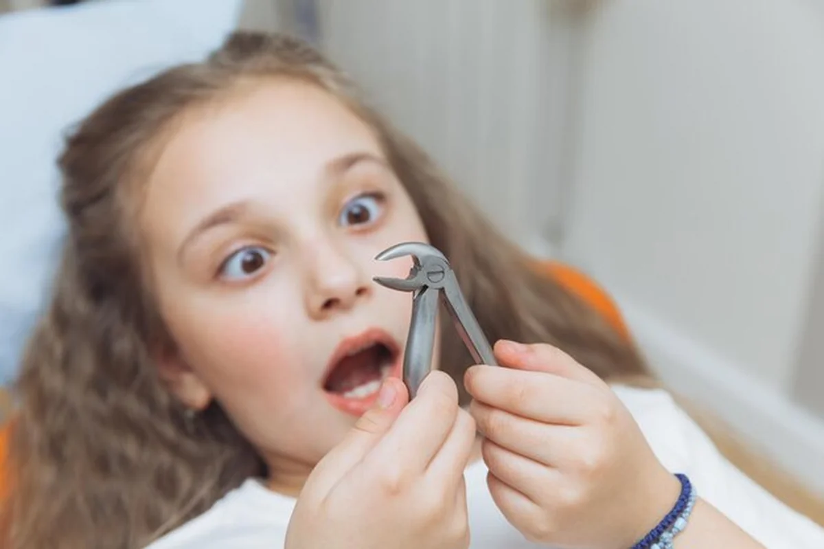 Przestraszona dziewczynka po usunięciu zęba u dentysty