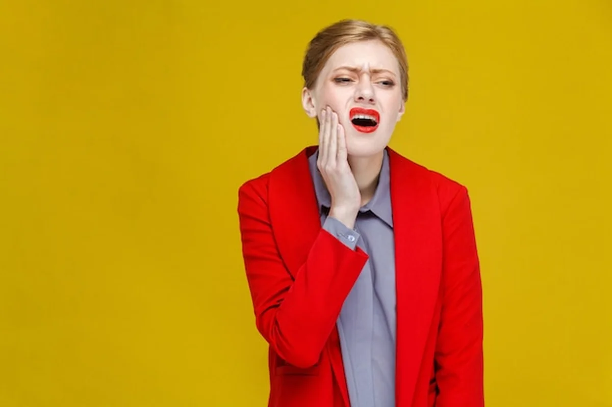 Kobieta w czerwonym garniturze z bólem zęba
