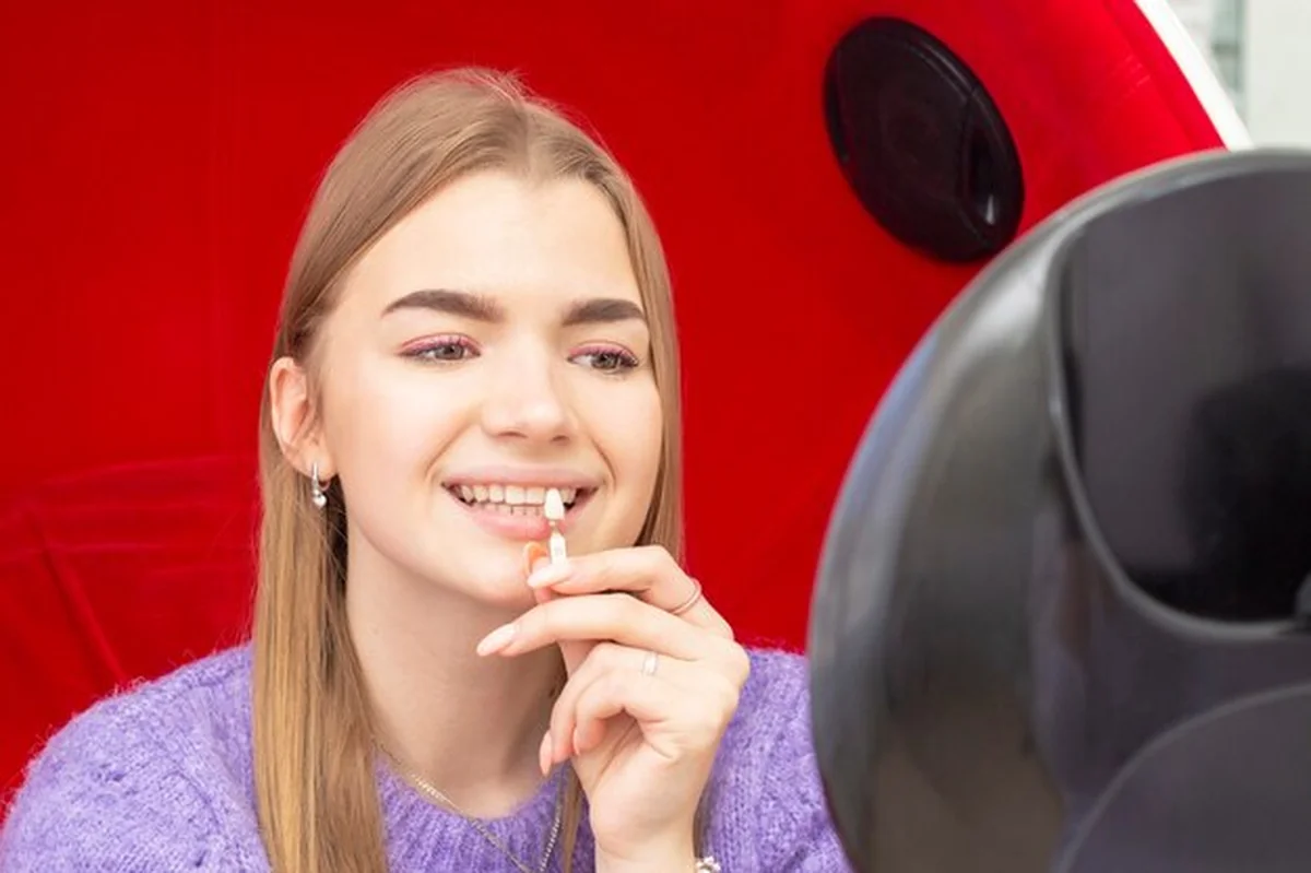 Dziewczyna wybielająca zęby patrząca w lustro