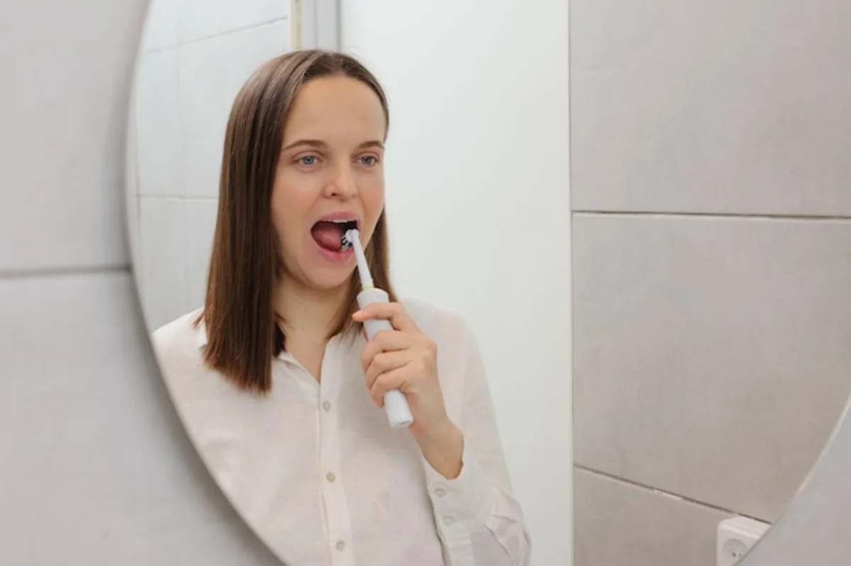 Młoda kobieta myjąca zęby przed lustrem w łazience
